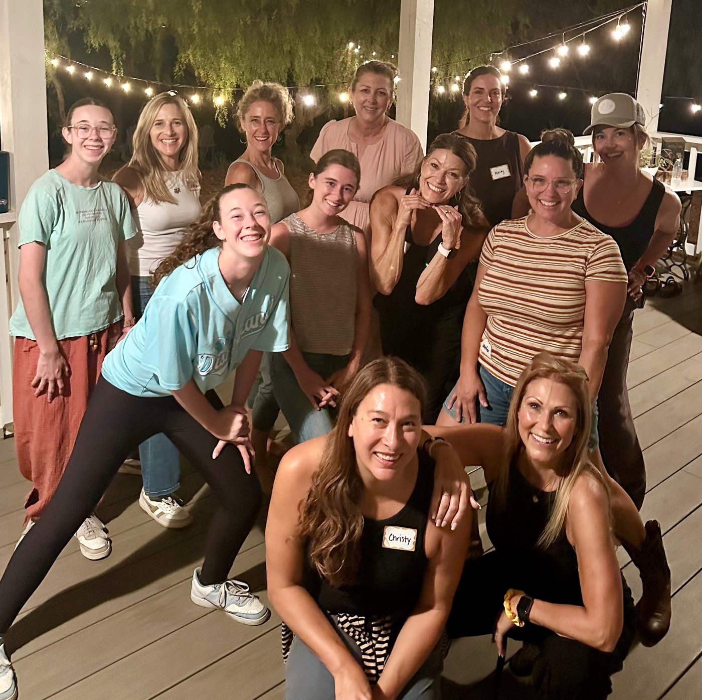 Group of women smiling together on a porch at night